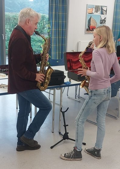 Ein Musiklehrer erklärt einer Schülerin das Saxophon.